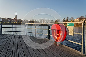 Red lifebuoy hanging on wooden pier, Jordan pond, Tabor, oldest dam in the Czech Republic, sunny autumn day, life insurance