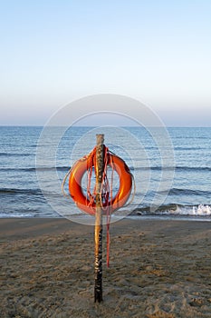 Red lifebuoy with rope on sandy beach, life save in sea water concept