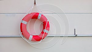 Red lifebuoy with white strip hanging on white wall