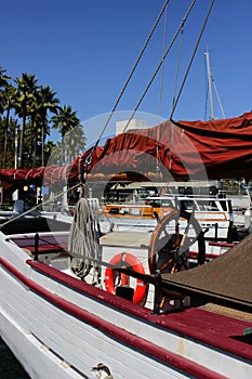 Red lifebuoy and wooden steering wheel on the deck of a sailing pleasure yacht moored in the tourist and recreational part of the