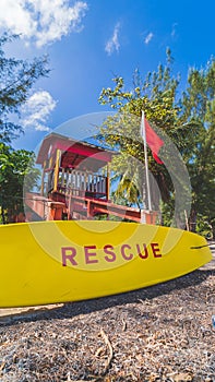 Red Lifeguard tower and yellow rescue board with red warning flag