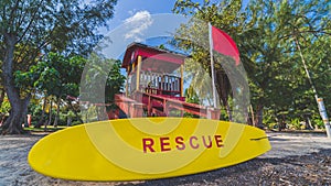 Red Lifeguard tower and yellow rescue board with red warning flag