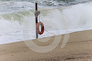 Red lifesaver on beach with breaking huge waves