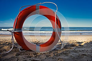 Red lifesaver ring standing upright on a beach