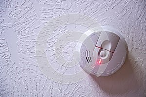 Red light batter indicator on a smoke detector mounted on a ceiling