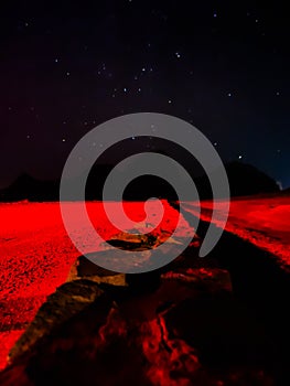 Red light on an empty brick and sandy path in the desert under the stars at night