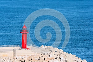 Red light house with ocean water in background
