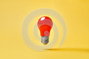 Red lightbulb levitate on yellow background. Idea, motivation concept