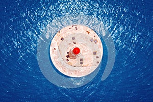 Red lighthouse against blue water of sea. contrast colors. Top aerial view