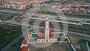 Red lighthouse drone view at seaside town. Urban infrastructure in port city.