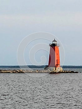 Red lighthouse extending into lake in Upper Michigan