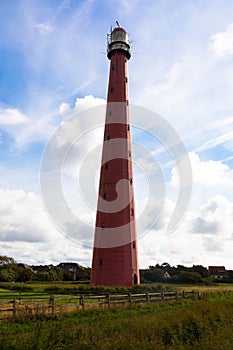 Red lighthouse in the harbor village den Helder against blue sky with cumulus clouds. photo