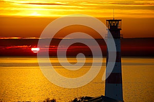 Red Lighthouse with Light Beam at Sunset. The top