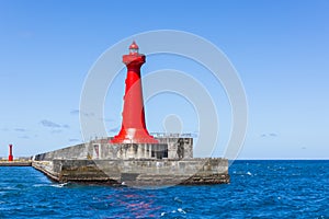 Red lighthouse over concrete pier in Hualien harbor of Taiwan