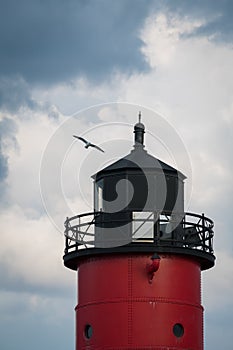 Red Lighthouse with Seagull against Cloudy Sky photo