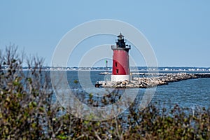 A red lighthouse shown with dune grass and brush in the foreground