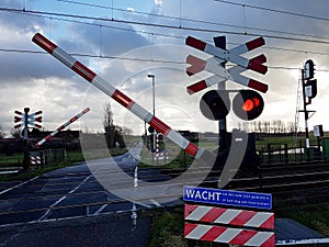 Red lights and bells warn that barrier goes down on a railroad crossing