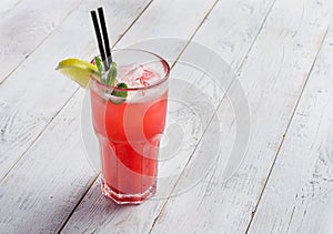 Red limonade in glass on white wooden background. With space for your text.