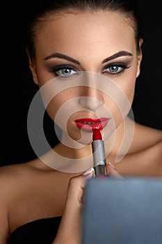 Red lips. Beutifull Woman Doing Makeup Applying lipstick