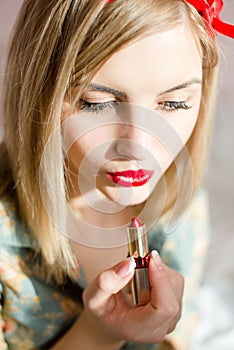 Red lips: blonde pinup woman draws red lipstick