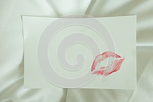 Red lips kiss blank white note good morning message on bed
