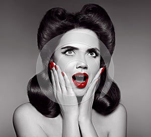 Red lips and manicured nails. Surprised pin up girl holds cheeks photo