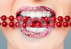 Red lips and white healthy teeth with bright pearls closeup. Perfect female smile with glitter lipstick makeup