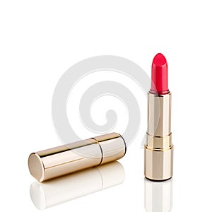 Red lipstick in golden tube on white background with mirror reflection on glass surface isolated close up, shiny gold lipstick