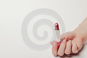 Red lipstick held in female hand, copyspace