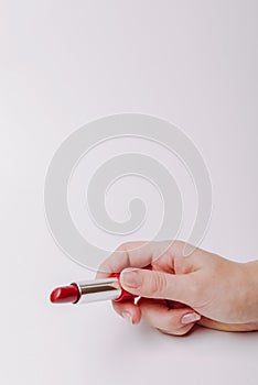 Red lipstick held in female hand, copyspace