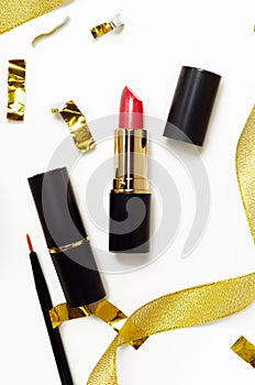 Red lipstick and lip brush top view composition. Makeup accessories and golden decorations on white background. Beauty industry