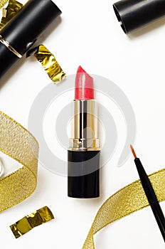 Red lipstick and lip brush top view composition. Makeup accessories and golden decorations on white background. Beauty industry