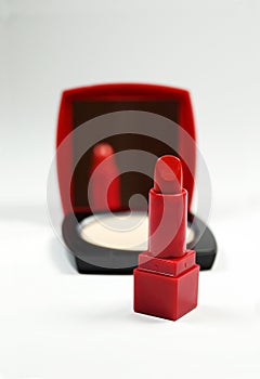 A red lipstick and a red-black powder compact with a mirror