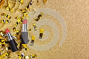 Red lipstick on a shiny golden background with glitter top view. Women`s beauty cosmetic product for professional lip makeup.