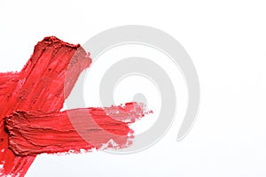 Red lipstick smear on white background, top view.