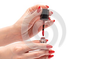 Red liquid lipstick in woman hands with red nails isolated on a white background