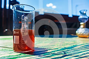 Red liquid in a measuring transparent glass stands on the table