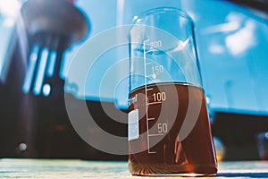 Red liquid in a measuring transparent glass stands on the table