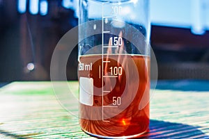 Red liquid in a measuring transparent glass stands on the table