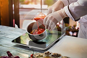 Red liquid pours into saucepan.