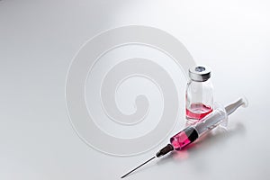 Red liquid vitamin B12 in a disposable syringe with a needle and in a glass ampoule on a white background. photo