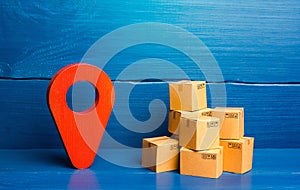 Red location pin pointer symbol and cardboard boxes. Improving the efficiency, speed and low cost of delivering goods to consumer