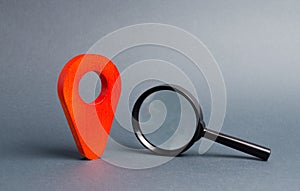 Red location pointer and a Magnifying glass on a gray background. Concept of navigation and venue. Tourism and travel. Spying