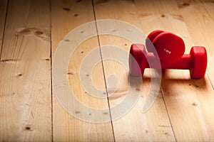 Red loght dumbbells on a wooden flor photo