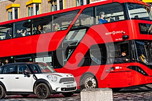 Red London Bus With Passenger And A White Mini Car Travelling On A Road