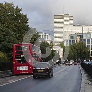 Red London buses during the rush hour in central London taking passengers to and from work and shopping crossing a box junction