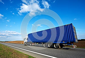 Red lorry with grey trailer over blue sky