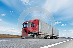 Red lorry with grey trailer over blue sky