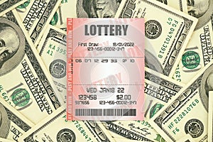 Red lottery ticket lies on big amount of hundred dollar bills. Lottery playing concept or gambling addiction. Close up