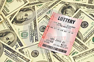 Red lottery ticket lies on big amount of hundred dollar bills. Lottery playing concept or gambling addiction. Close up